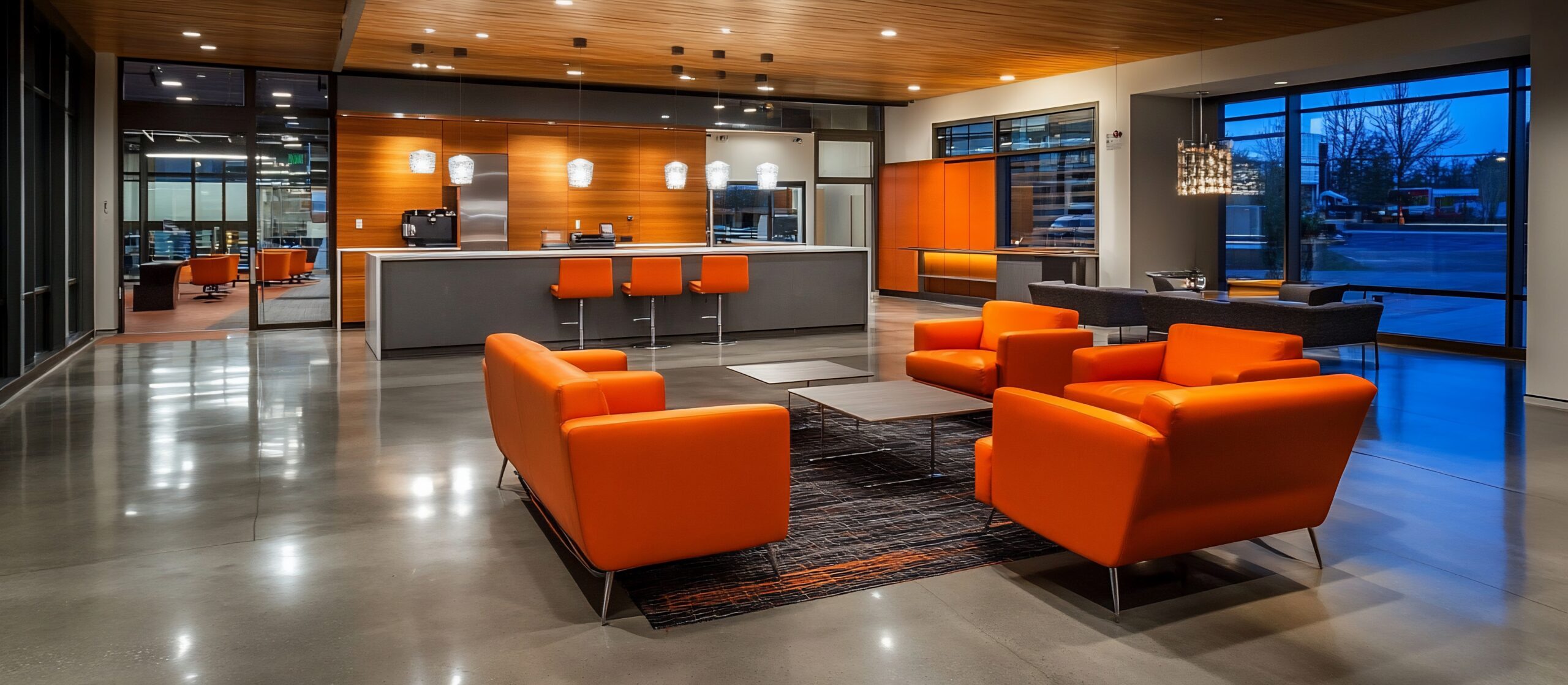 A modern and stylish lounge area with orange furniture and polished concrete floors. The space is elegantly designed, offering a relaxing ambiance.